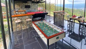 A room with a foosball table, bar area, and large windows offering a view of the outdoors. - SKYGREEN ECOHOTEL (Dosquebradas)