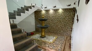 A staircase with a glass railing leading to a landing with a decorative fountain. - SKYGREEN ECOHOTEL (Dosquebradas)