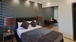 A modern hotel room with a large bed, bedside lamps, a small table, and a chair. - SKYGREEN ECOHOTEL (Dosquebradas)