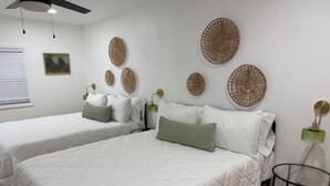 Habitación de hotel con dos camas queen, una mesa redonda y adornos textiles colgantes.