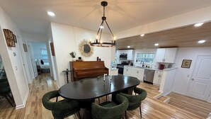 Una cocina moderna con armarios blancos, una mesa de comedor de madera y una araña.