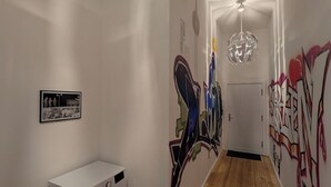 Un pasillo con lavadora, una lámpara en el techo y grafitis en las paredes.