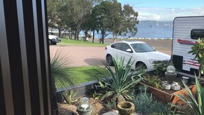 A view of a white SUV parked on a driveway with a boat trailer in the background. - Charming garden suite (Belmont)
