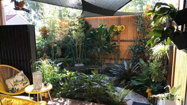 A wooden deck with a variety of potted plants and a small table with chairs. - Charming garden suite (Belmont)
