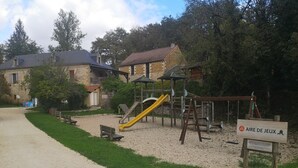 Un parque infantil con un tobogán amarillo, columpios y una estructura para escalar.