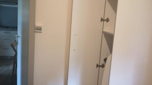 Un dormitorio con cama, armario y una mesita.