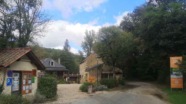 Un camino rural que lleva a un edificio pequeño con un letrero de recepción, un letrero de estacionamiento y un cartel con la palabra 'ANIMATIONS'.