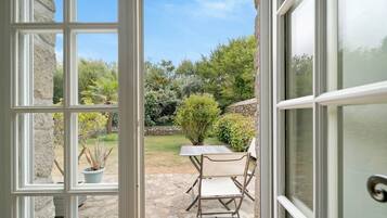 An open door to a patio with a stone floor, a table, and a chair.
