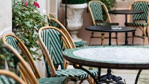 An outdoor seating area with wicker chairs and a round table, a lamp, and a potted plant. - Maison La Louise (Ligny-en-Barrois)