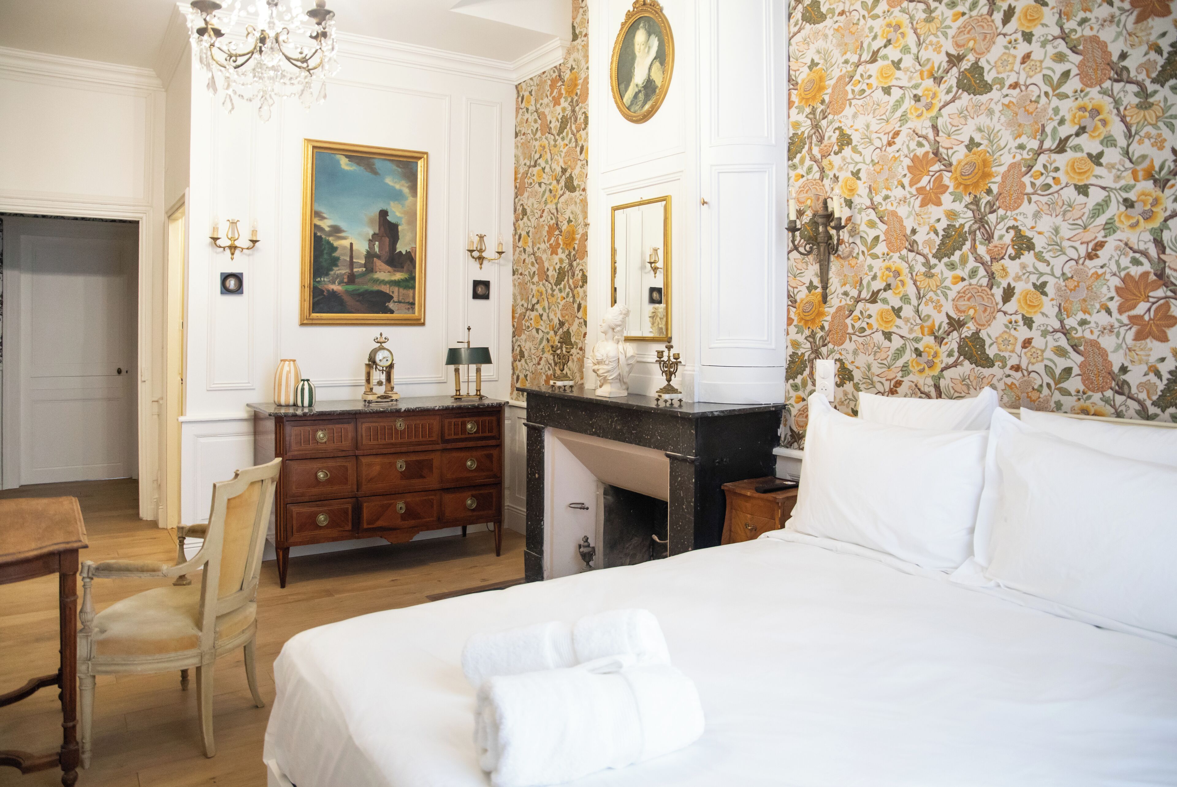Una habitación de hotel con una cama grande, un aparador de madera, un escritorio y una silla.