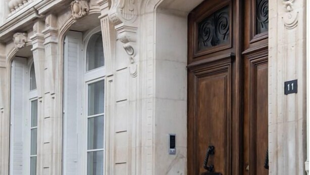 A building facade with ornate architectural details, including columns, decorative moldings, and a large wooden door with a number plaque. - Maison La Louise (Ligny-en-Barrois)