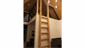 Ein Schlafzimmer im Spitzboden mit Holzboden und einer Holzlade, die zu einer geneigten Decke führt.