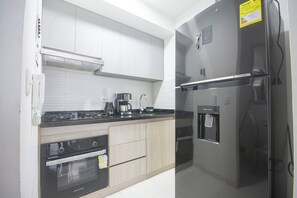 A modern kitchen with a built-in oven, a coffee maker, a water dispenser, and a refrigerator. - Spacious and centrally located ApartaSuite near the historic center (Torices)