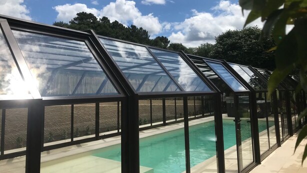 A glass-enclosed swimming pool with a clear blue sky and clouds above. - CASA CON ENCANTO O REFUXIO (Vila de Cruces)