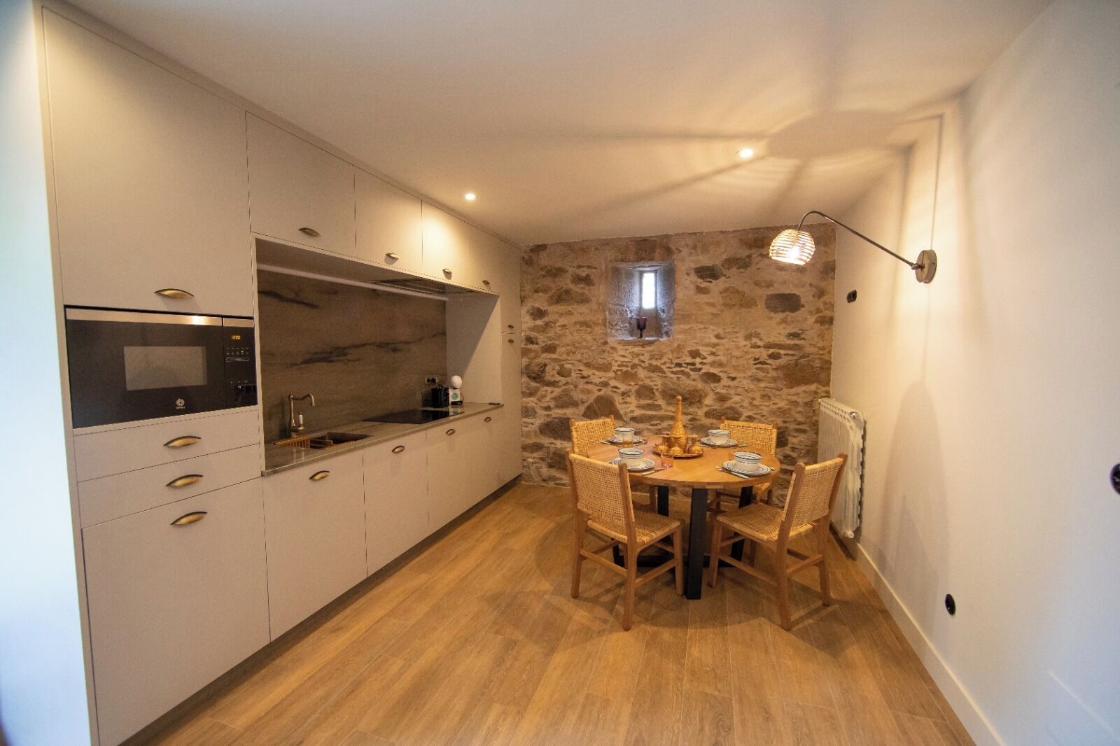 A compact kitchen with a stone wall, wooden dining table, and modern appliances.