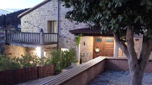 A stone building with a wooden bench and potted plants in the foreground. - CASA CON ENCANTO O REFUXIO (Vila de Cruces)