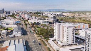 Ett modernt stadsområde med en blandning av kommersiella och bostadshus, en huvudgata och en vattendrag på avstånd.
