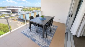 A balcony with a table and chairs, a view of buildings, and a clear sky. - Central Townsville CBD 1BR Apartment with Pool and Parking (Townsville City)