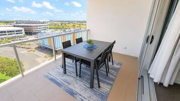 A balcony with a table and chairs, a view of buildings, and a clear sky.