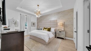 Un dormitorio moderno con una cama grande, mesitas de noche, una araña y un cabecero de madera.