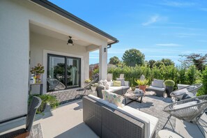 A covered patio with outdoor furniture, a potted plant, and a view of greenery. - Hidden Gem! Luxury Palm Home with Modern Comfort (LaBelle)