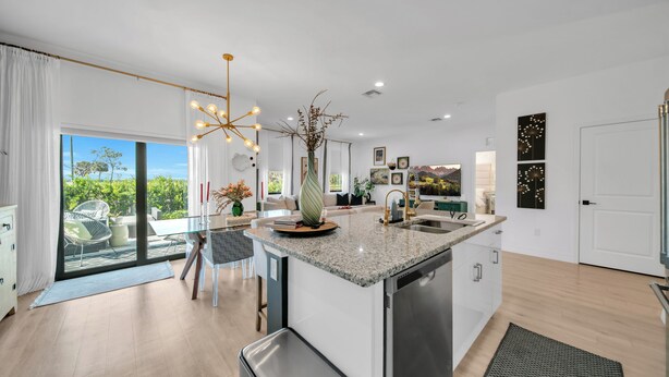 Una cocina moderna con una isla central, un comedor con mesa de vidrio y vistas amplias por grandes ventanales.