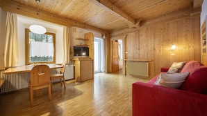 Een houten interieur met een eetgedeelte, een rode bank en een keuken.