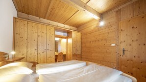 Een houten kamer met twee bedden, een bureau en een stoel.