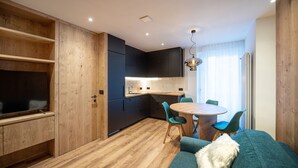 Une cuisine compacte avec des meubles en bois, une table à manger avec des chaises et un canapé agrémenté d’un coussin décoratif.
