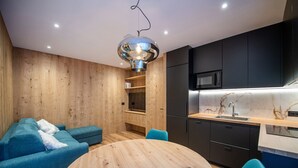 Une cuisine moderne avec des meubles de couleur sombre, un four à micro-ondes et une table à manger en bois, accompagnée de chaises.