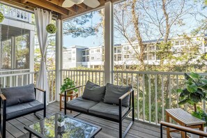 A covered outdoor seating area with a sofa and chairs, a table, and potted plants. - Rehoboth Crossing 1 For 10 (Rehoboth Beach)