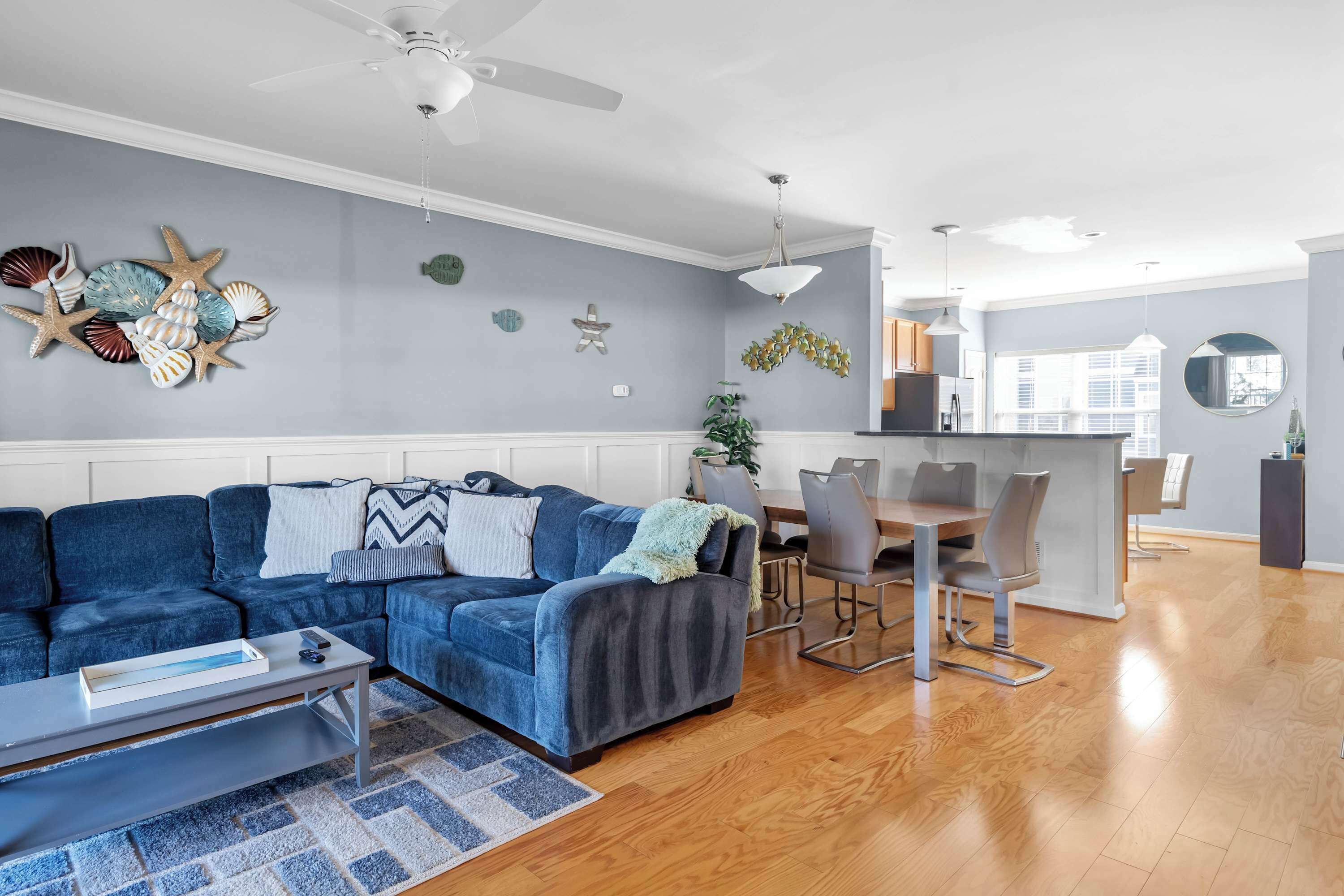 Una sala de estar moderna con un sofá azul, una mesa de comedor y una zona de cocina al fondo.