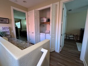 Une buanderie équipée d’un lave-linge et d’un sèche-linge, d’une petite table et d’une chaise.