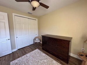 A room with a wooden dresser, a chair, a ceiling fan, and a door. - Ole’ at Lely Resort. Adorable 2-bedroom casita, perfect for relaxing stays (Naples Fl.)