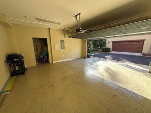 A garage with a concrete floor, a ceiling fan, and a garage door. - Ole’ at Lely Resort. Adorable 2-bedroom casita, perfect for relaxing stays (Naples Fl.)