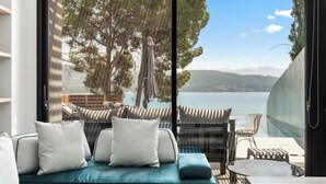 Ein moderner Außenbereich mit einer Sitzecke, einer Couch und Sesseln, mit Blick auf einen malerischen See und Berge.