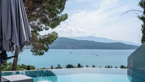Ein Pool ohne Ende mit Blick auf Meer und Berge.