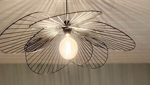 A neatly made bed with white linens, two bedside lamps, and a unique ceiling light fixture. - Le Rissas, gite for 4 _ Lacets Ventoux (Beaumont-du-Ventoux)
