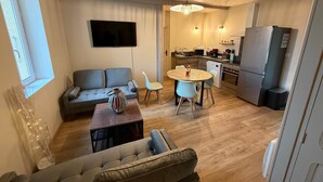 A modern living room with a sofa, a dining table, and a kitchen area with appliances. - Le Rissas, gite for 4 _ Lacets Ventoux (Beaumont-du-Ventoux)