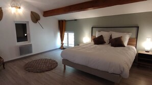 A bedroom with a large bed, a chair, a round rug, and wall-mounted lights. - Le Ventoux, gîte for 5 _ Lacets du Ventoux (Beaumont-du-Ventoux)