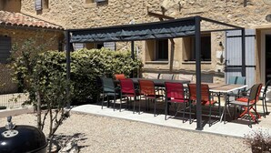 A stone building with a covered patio, outdoor seating, and a barbecue grill. - Le Ventoux, gîte for 5 _ Lacets du Ventoux (Beaumont-du-Ventoux)