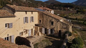 A traditional stone building with a courtyard, featuring multiple windows and a tiled roof. - Le Ventoux, gîte for 5 _ Lacets du Ventoux (Beaumont-du-Ventoux)