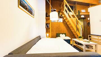 Een knus vertrek met een bed, houten wanden, een trap en een boekenplank.