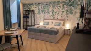 A bedroom with a bed, bedside tables, a desk with chairs, a wardrobe, and a view of the outdoors. - Green Dream Retreat (Linz)