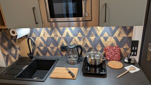 A modern kitchen with a stainless steel microwave, a sink, a coffee maker, and a cutting board. - Green Dream Retreat (Linz)