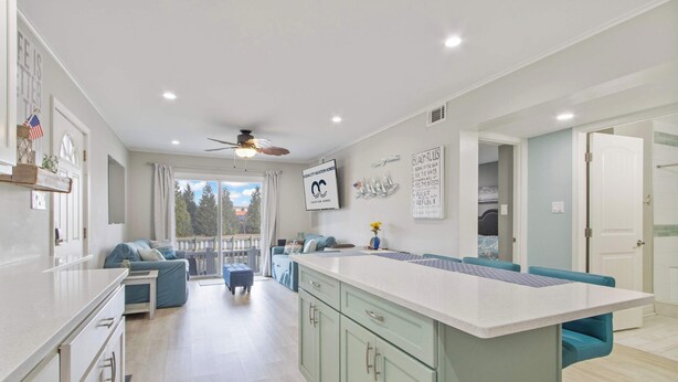 A modern kitchen with a central island, light-colored cabinets, and a ceiling fan. - 110A Newport Bay ,Deck Seating , Pool , WaterView (Ocean City)