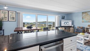 Una cucina moderna con una grande isola, zona pranzo con sedie e vista sull'oceano.