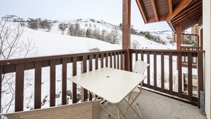 Ein Balkon mit Tisch und Stühlen mit Blick auf eine verschneite Berglandschaft.