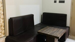 A corner seating area with a dark leather sofa and a wooden coffee table. - 5-bedroom upper house in Wayanad for a relaxing getaway (Kalpetta)