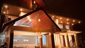 A modern two-story house with a wooden exterior, a balcony, and a staircase leading to the upper floor. - 5-bedroom upper house in Wayanad for a relaxing getaway (Kalpetta)